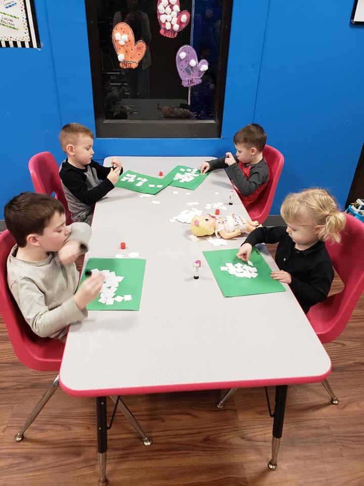 Four children sitting at a table doing crafts