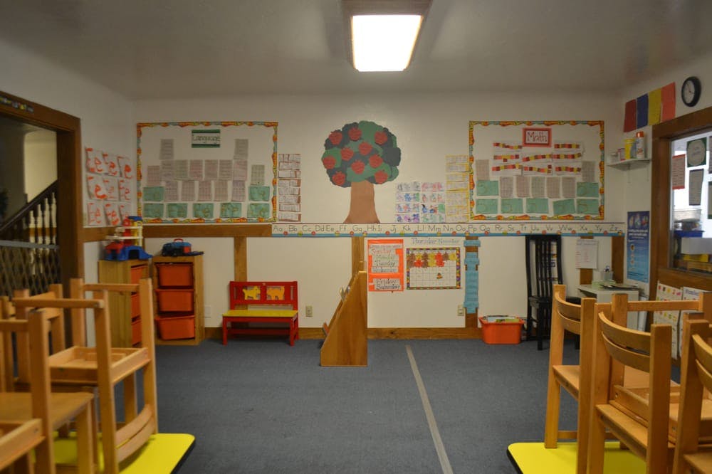 Classroom with small wooden chairs, a red bench, and wall decorations