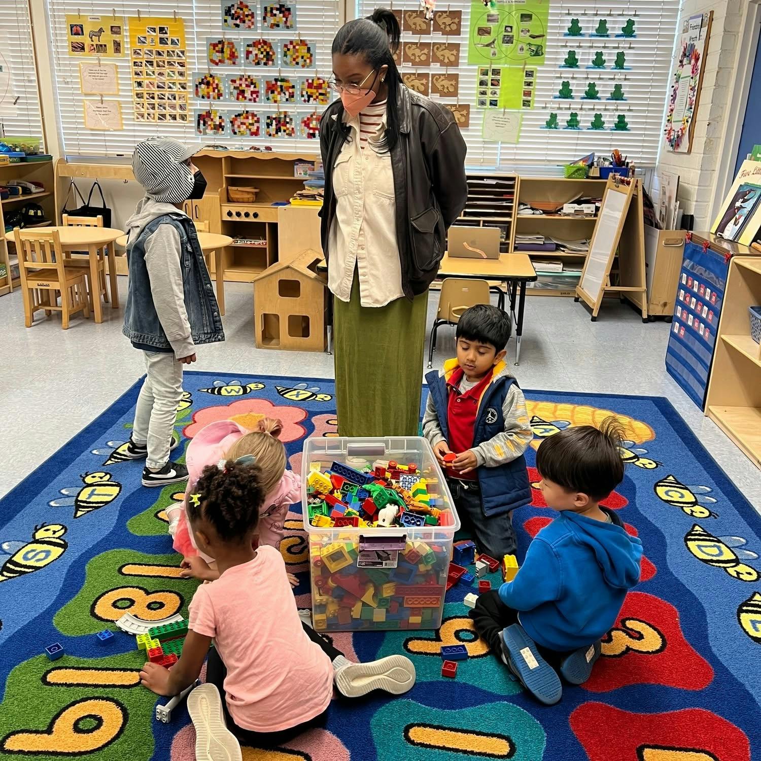 Adult supervising children playing with blocks in a classroom