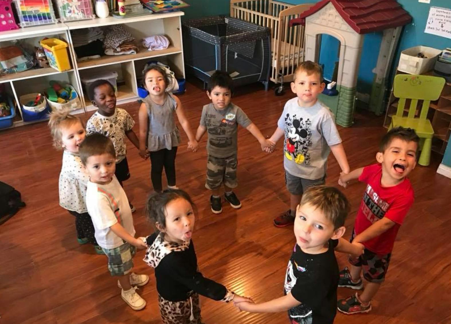 Children holding hands in a circle in a classroom