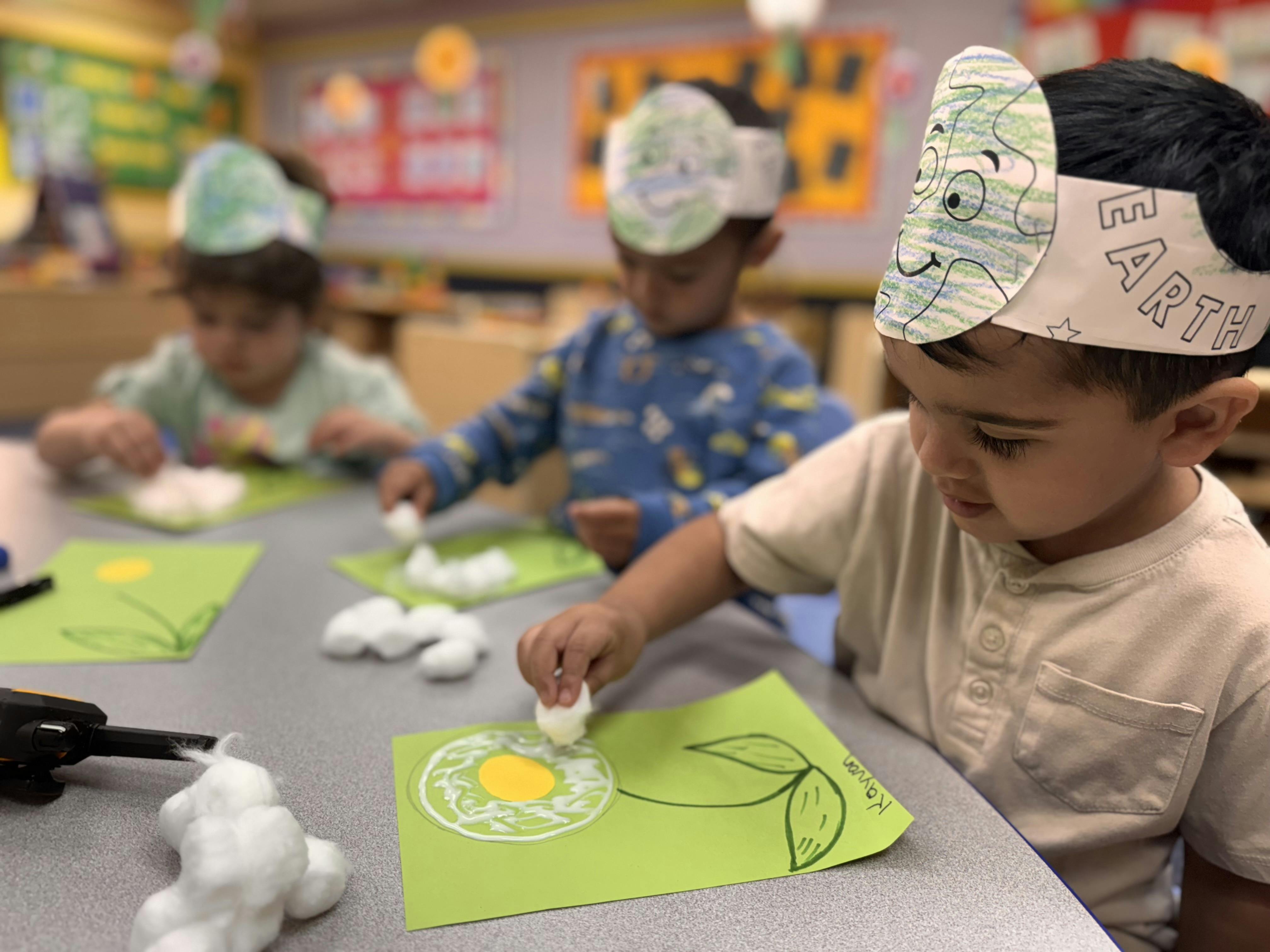 Children in a classroom doing an art activity with cotton balls