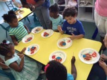 Children at a table with plates of colorful art projects