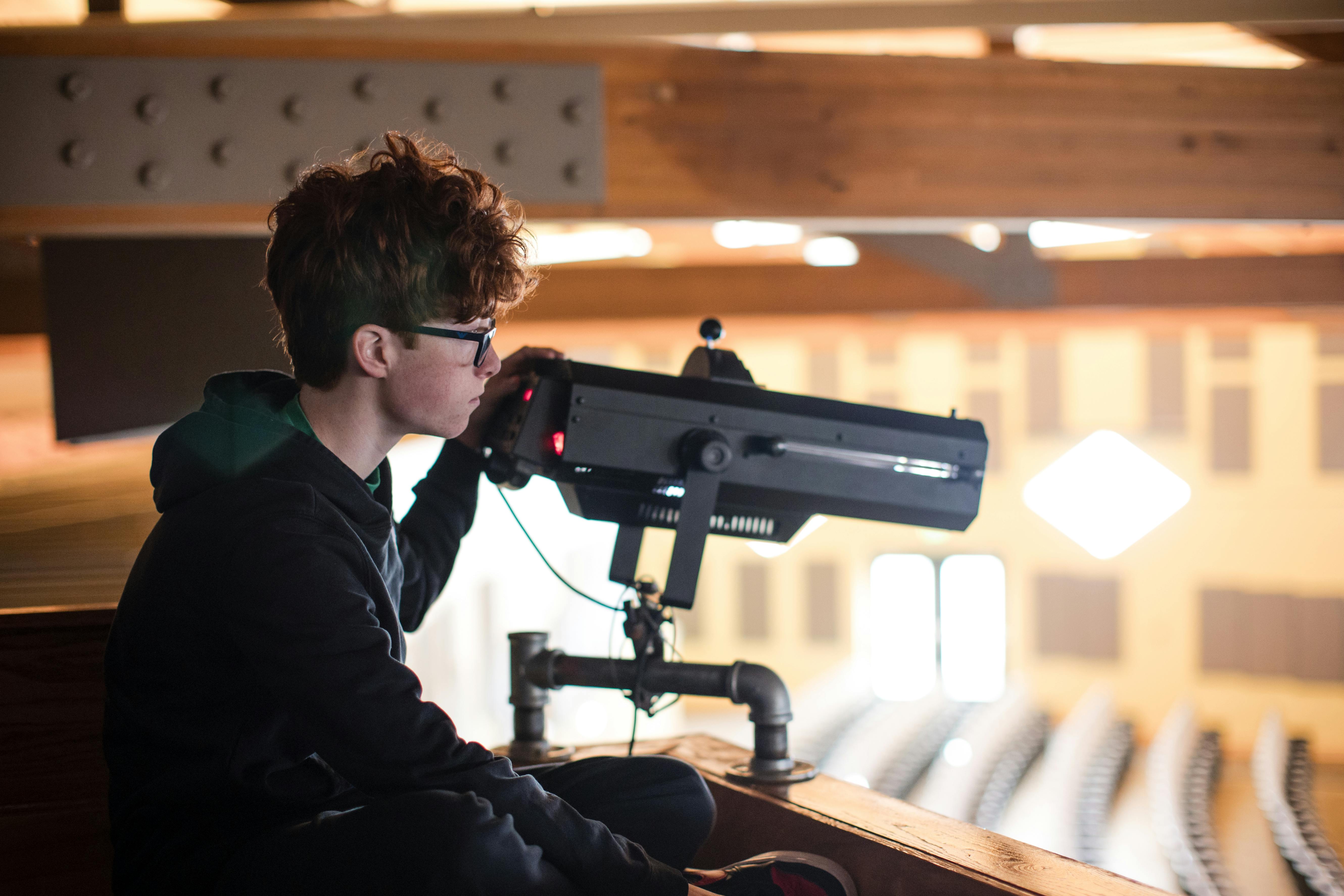 Teen looking through a large camera or scope