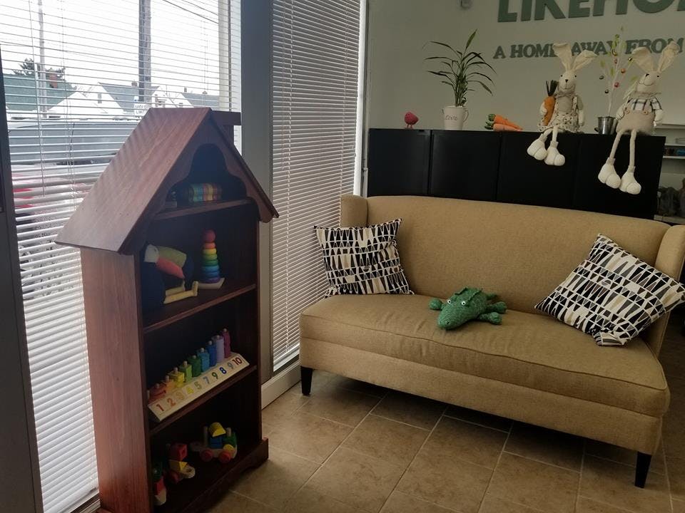 House-shaped bookshelf with toys next to a couch with pillows