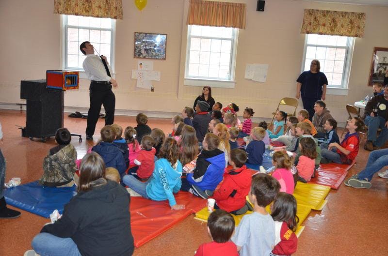 Person performing for a group of children and adults sitting on the floor