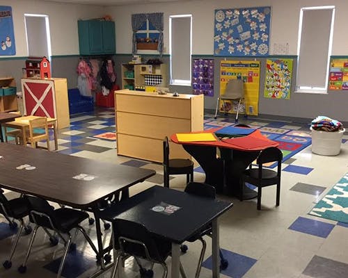 Classroom with tables, chairs, and educational posters on the walls