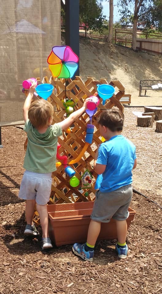 Two children playing with a water wall