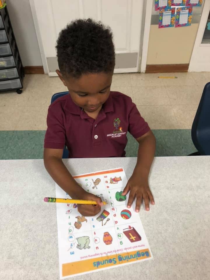 Child writing on a worksheet with a pencil