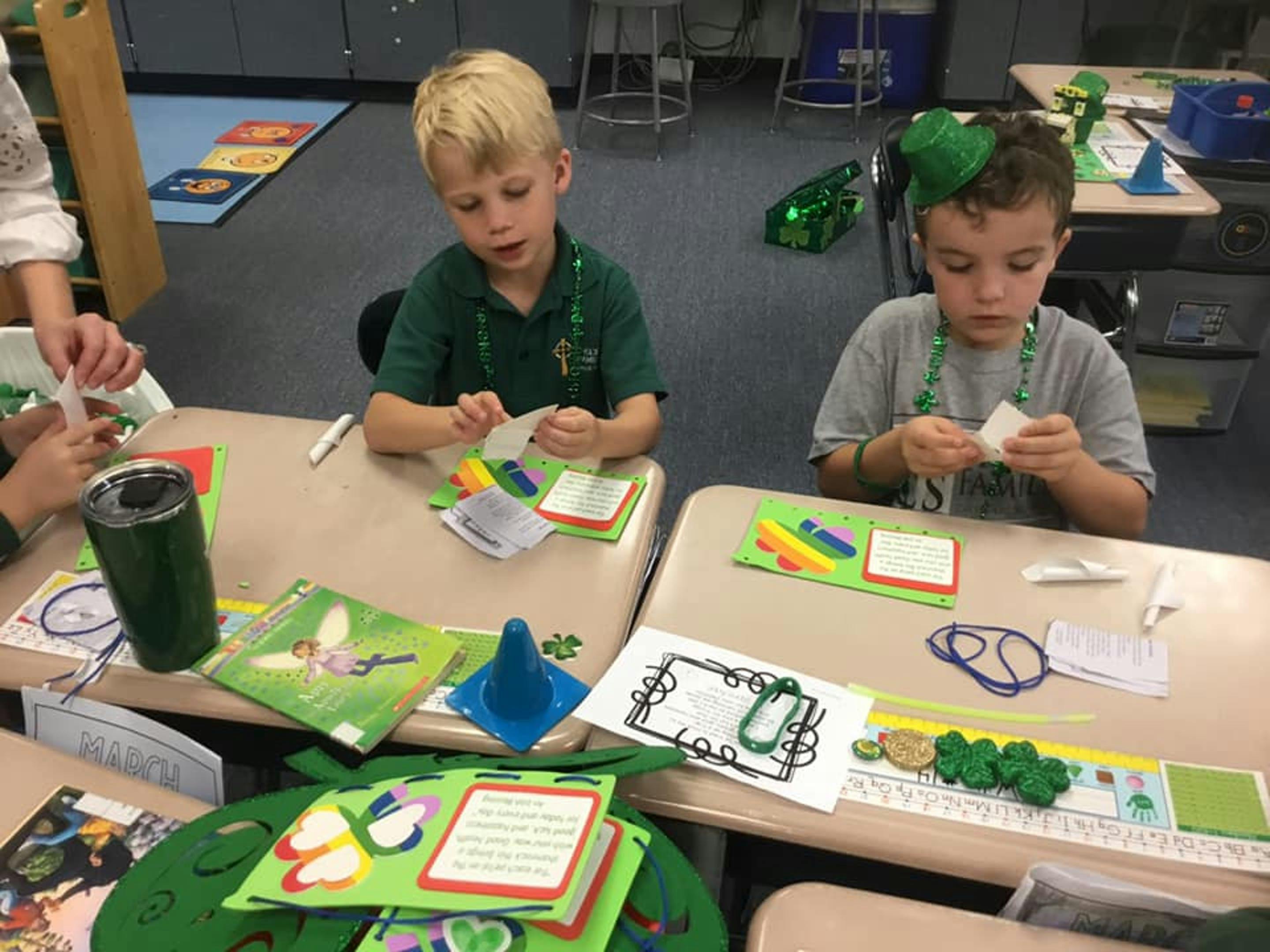 Two children working on crafts at desks in a classroom