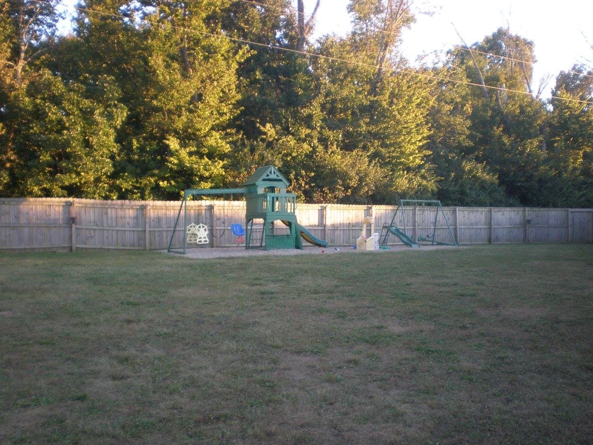 Playground with green slide and swings in a grassy area
