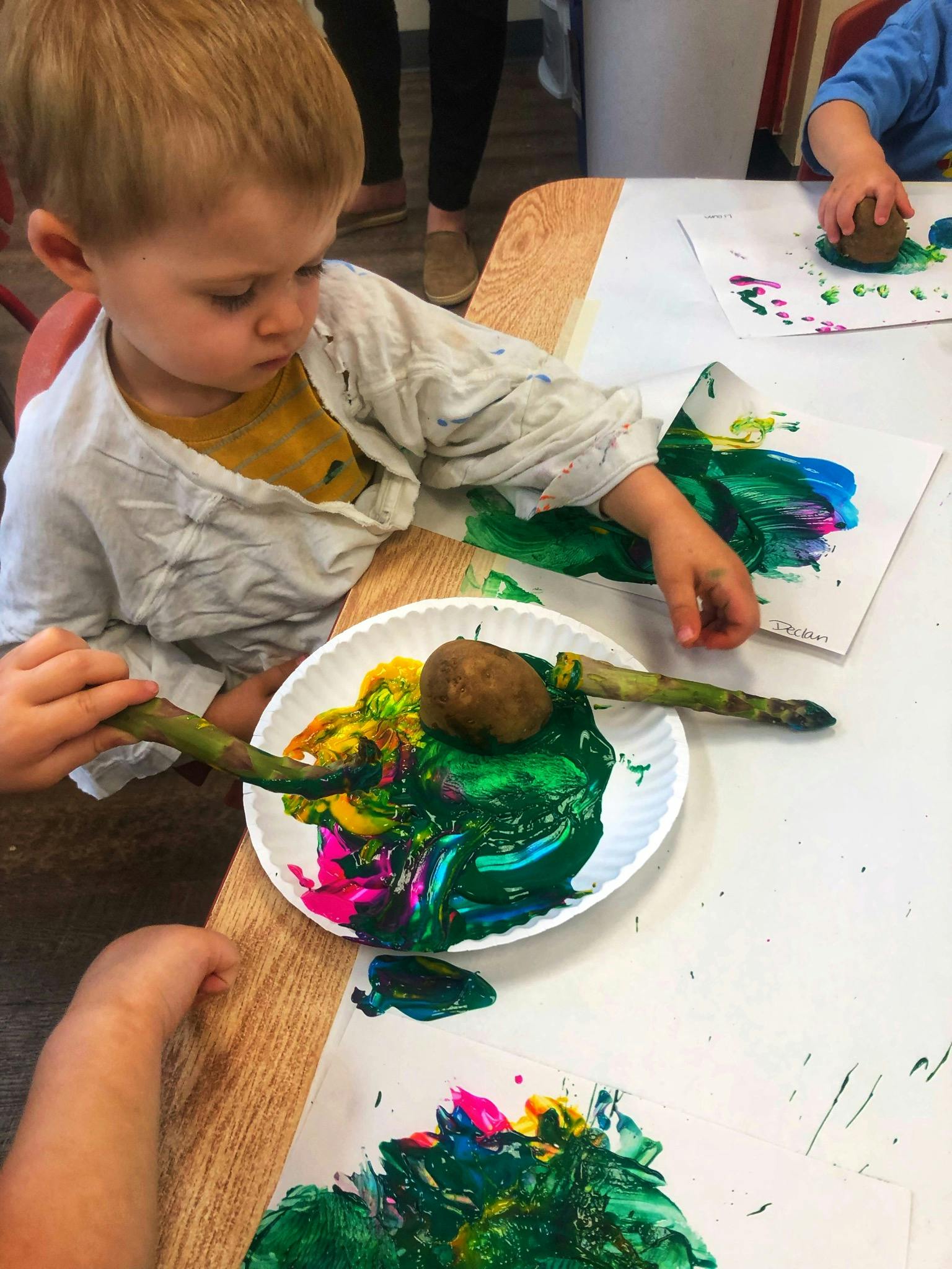 Child painting with a potato and stick