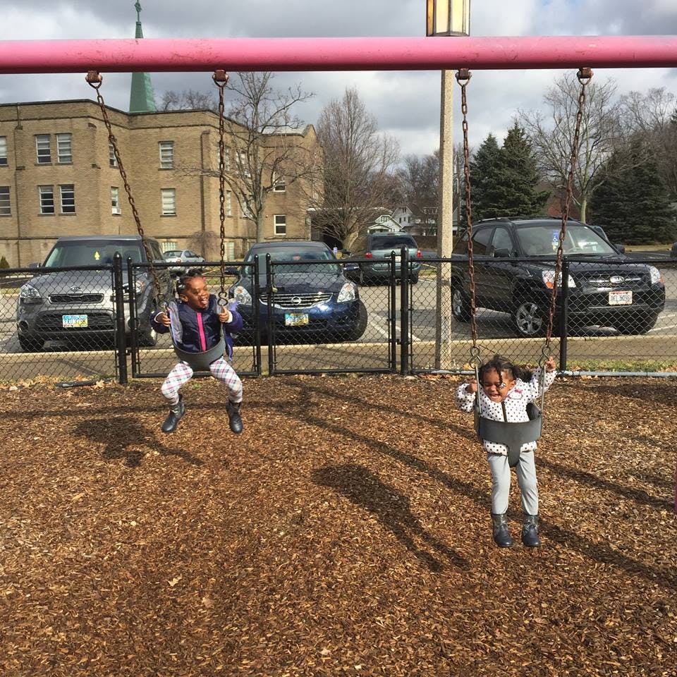 Two children swinging on a playground