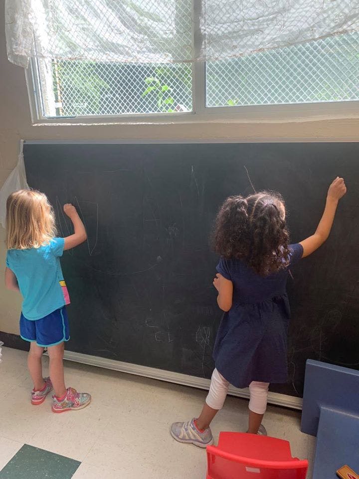 Two children drawing on a chalkboard