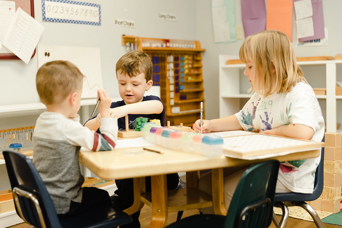 Three children at a table in a classroom