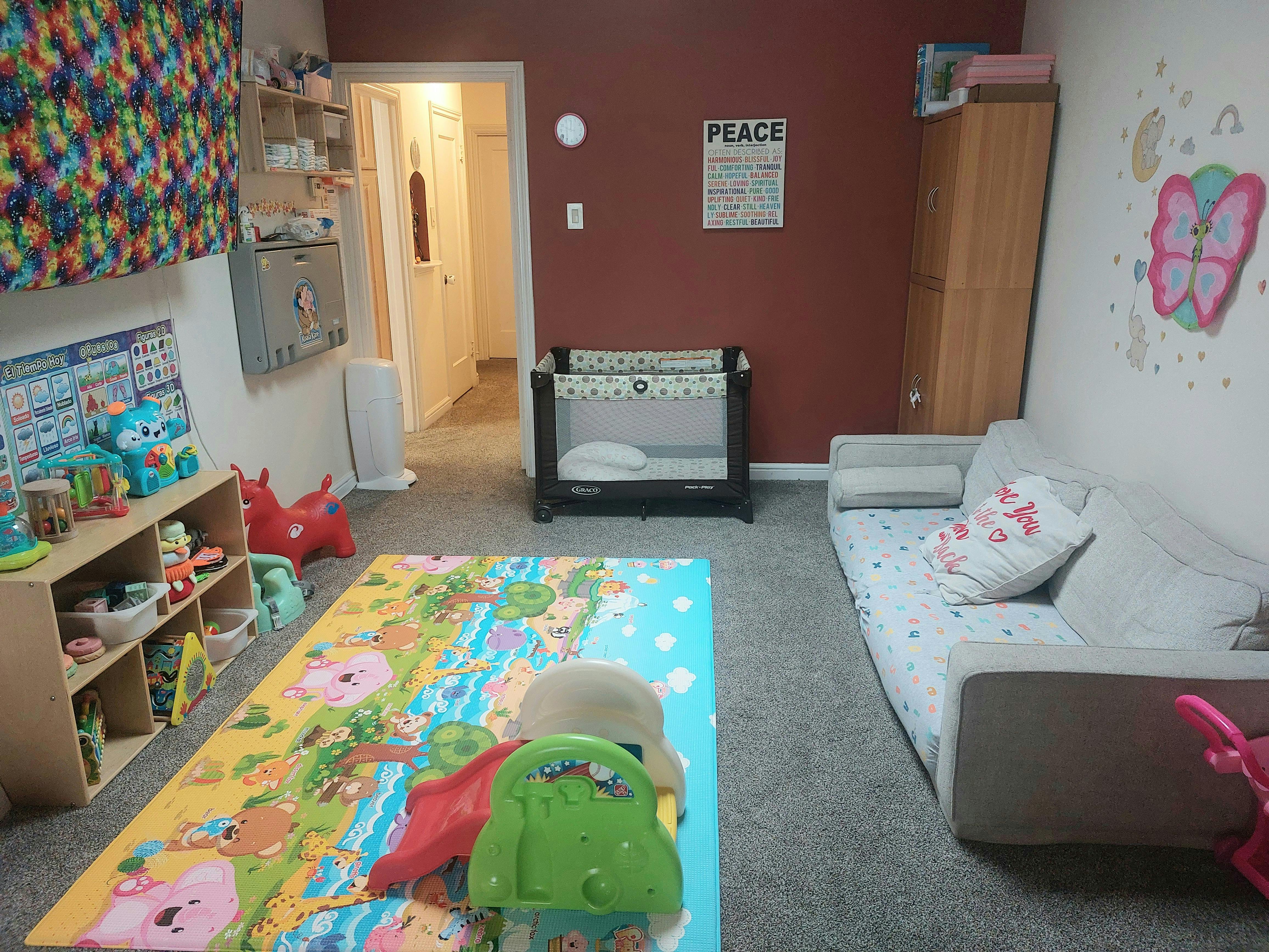 Playroom with a colorful rug, crib, and sofa