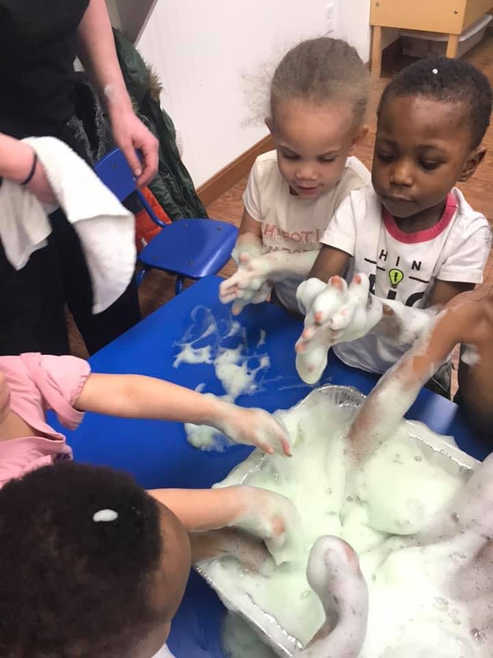 Children playing with foam in a blue bin