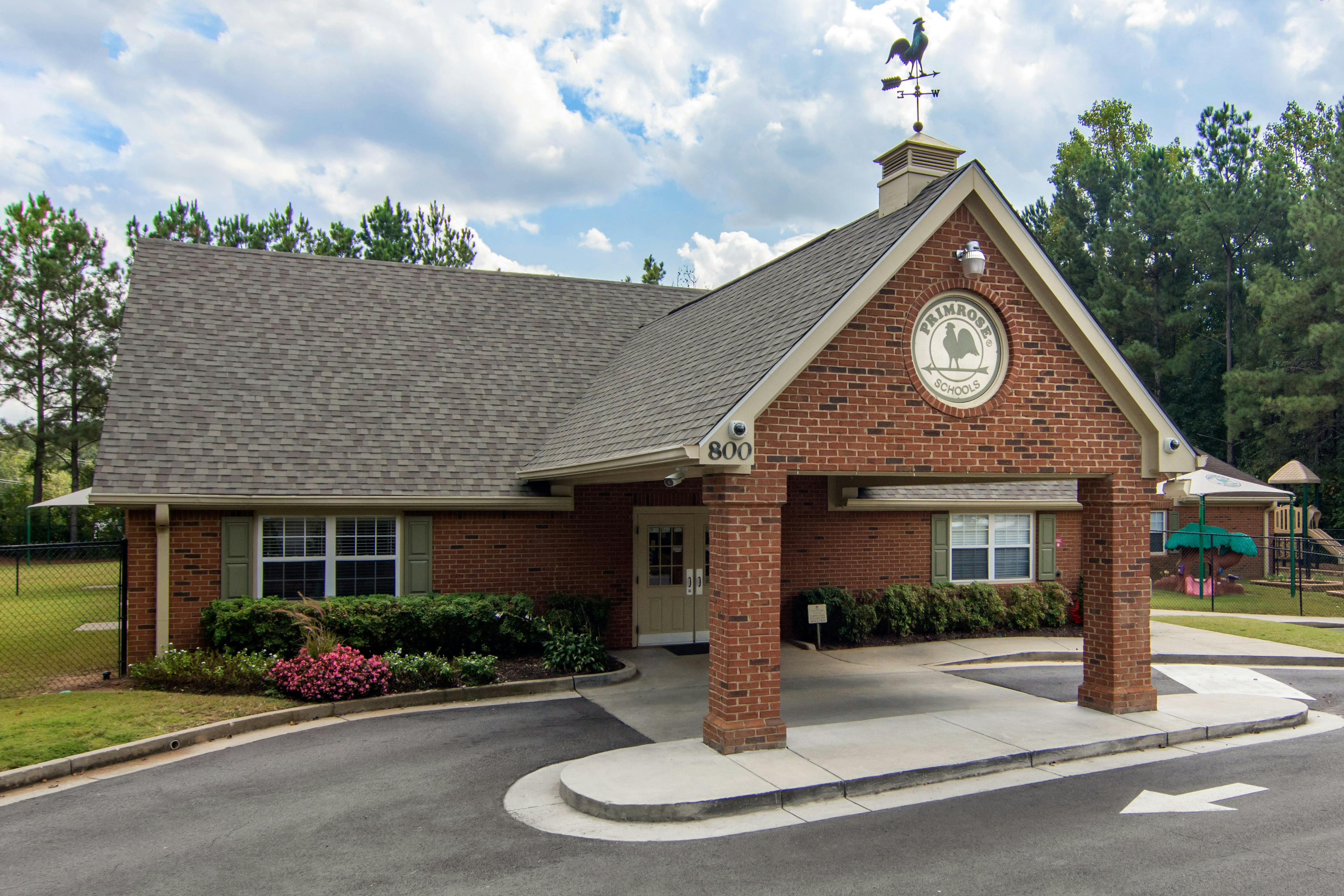 Brick building with a weather vane on the roof and a sign for Primrose Schools