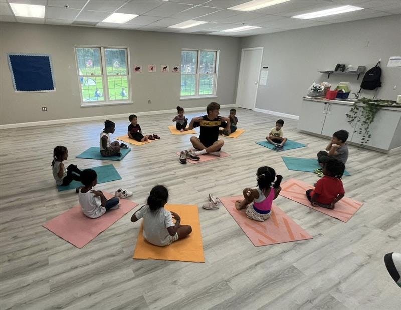 Adult and children sitting on yoga mats in a room