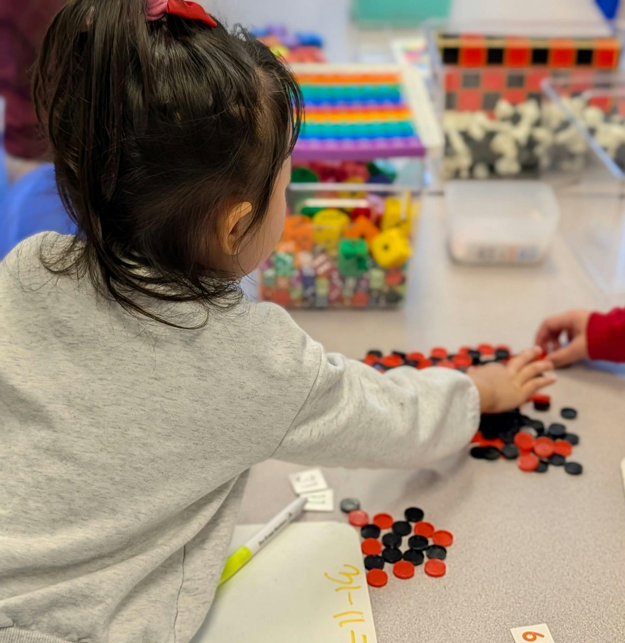 Child manipulating red and black counters in a classroom