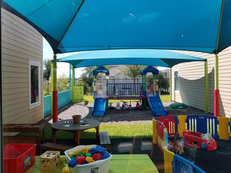 Outdoor playground with slides and play structures under a blue canopy