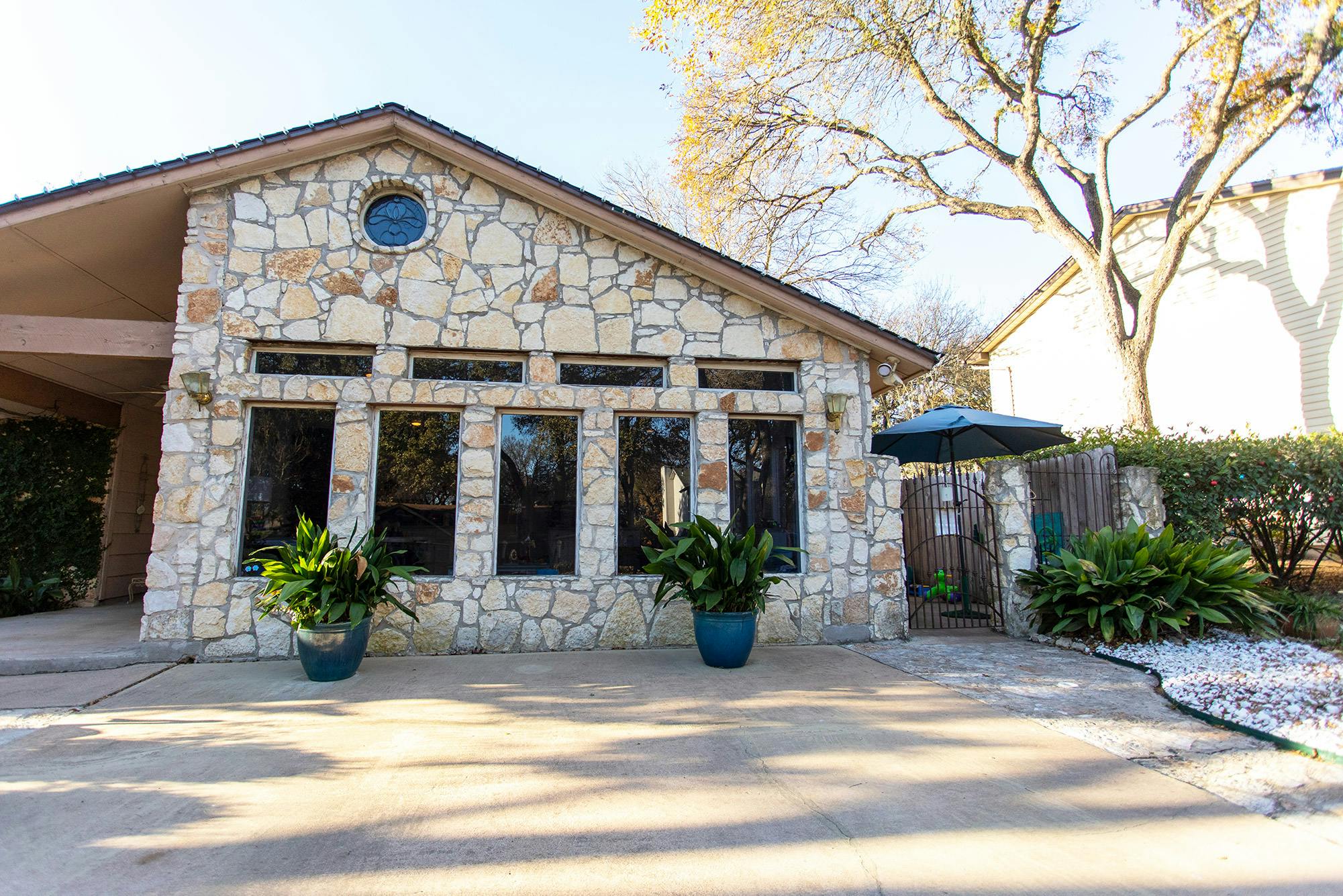 Stone building with large windows and potted plants outside