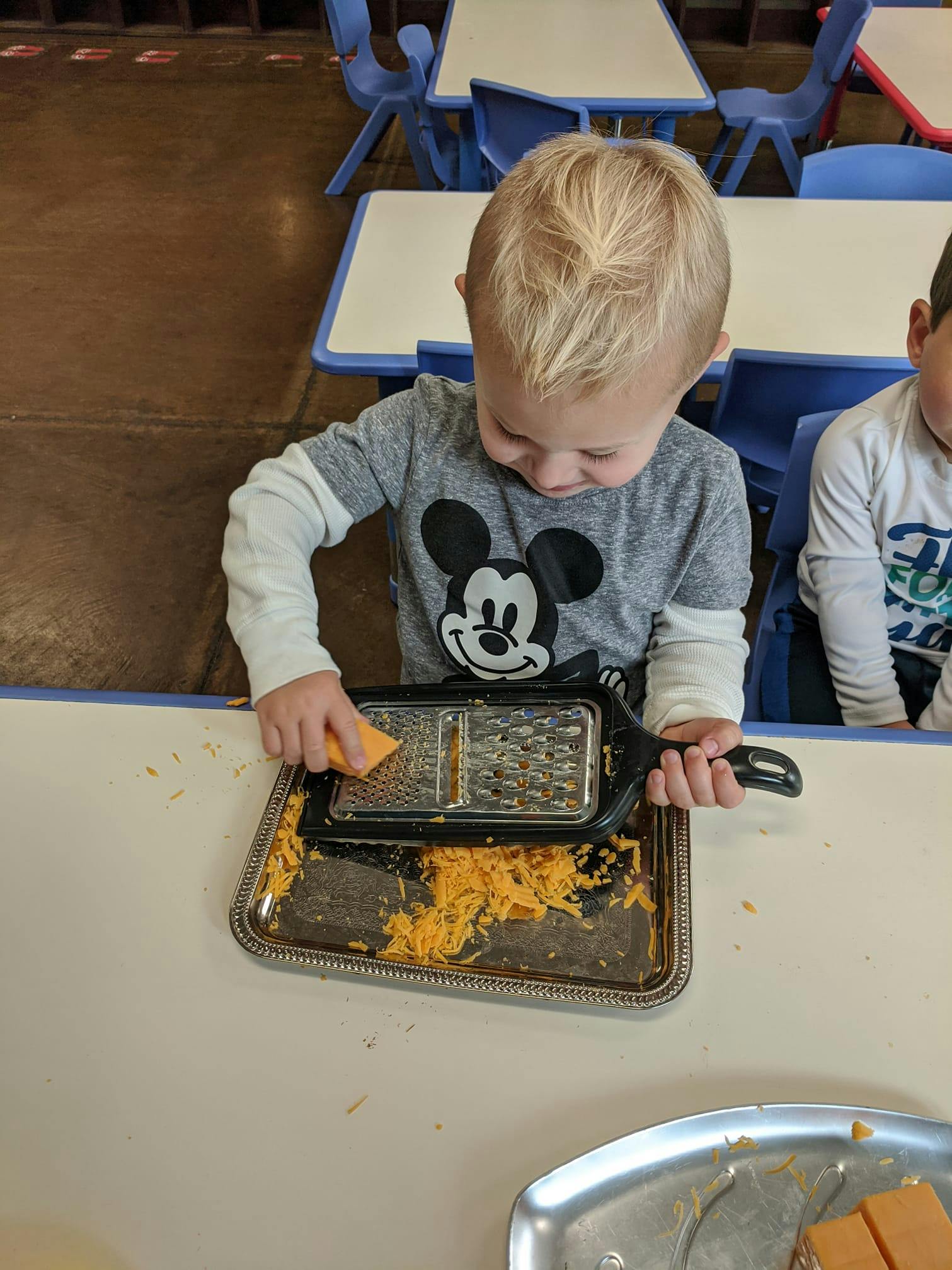 Child grating food onto a tray