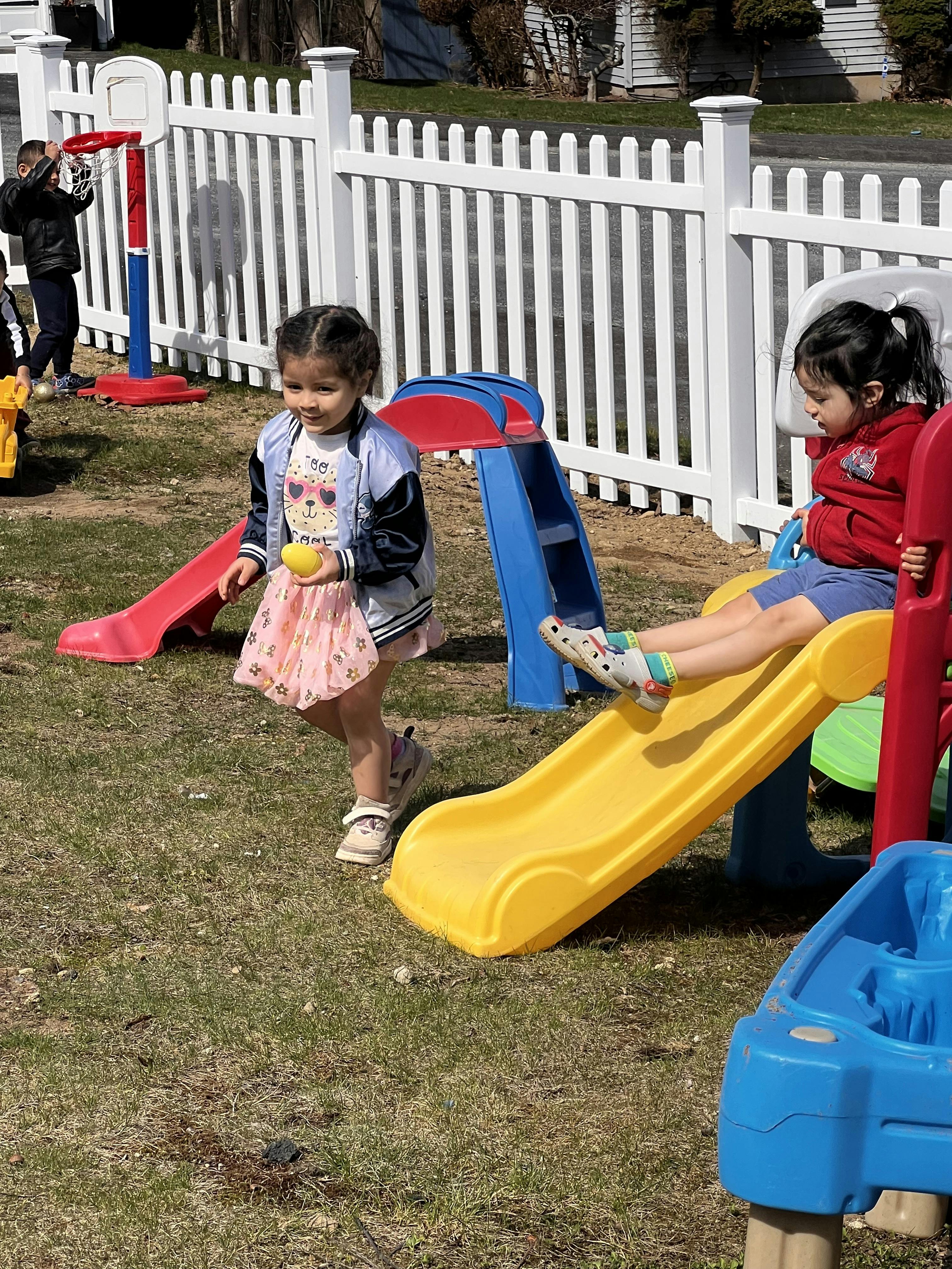 Two children playing on slides outdoors
