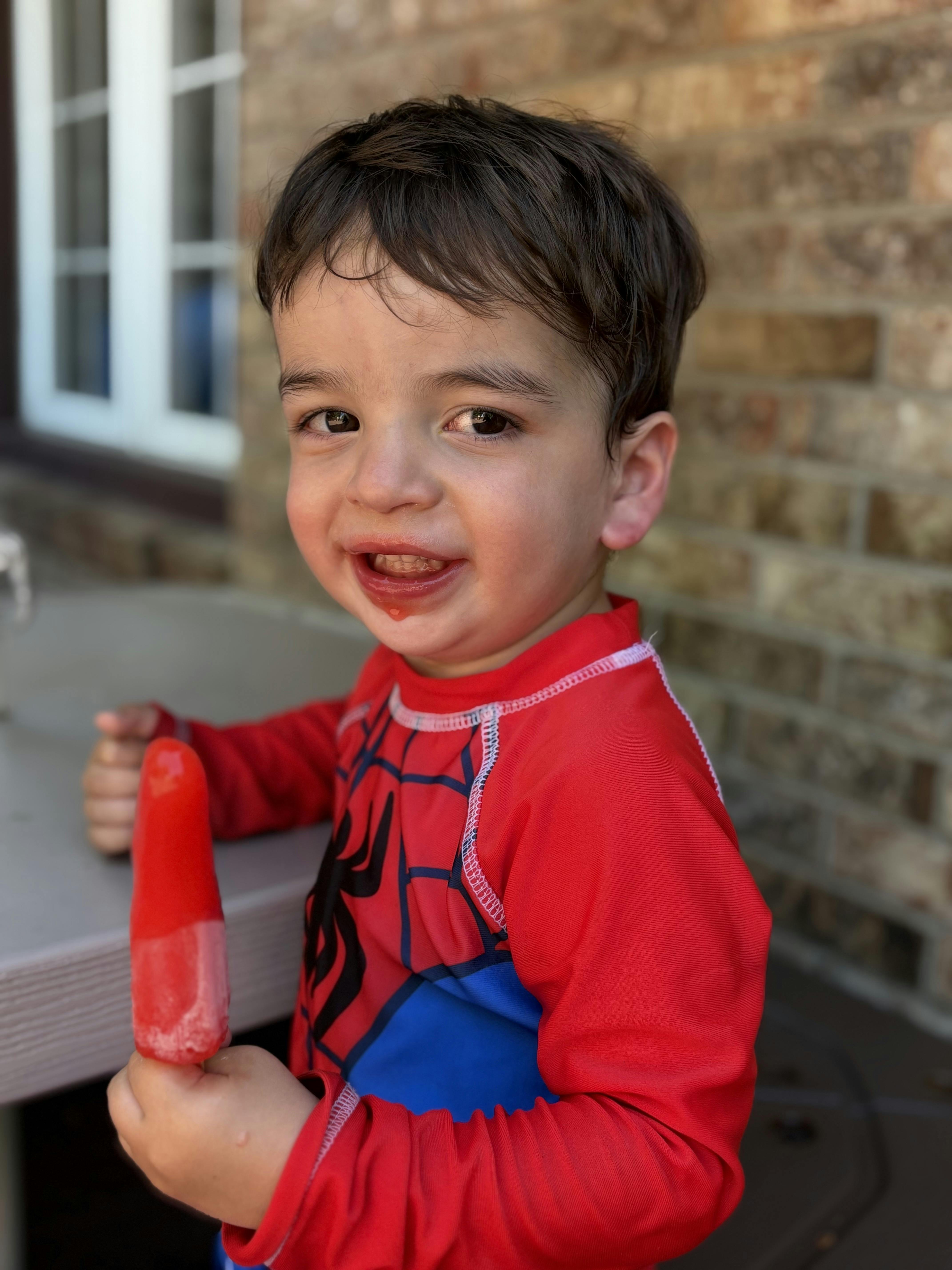 Child in red shirt holding a red popsicle