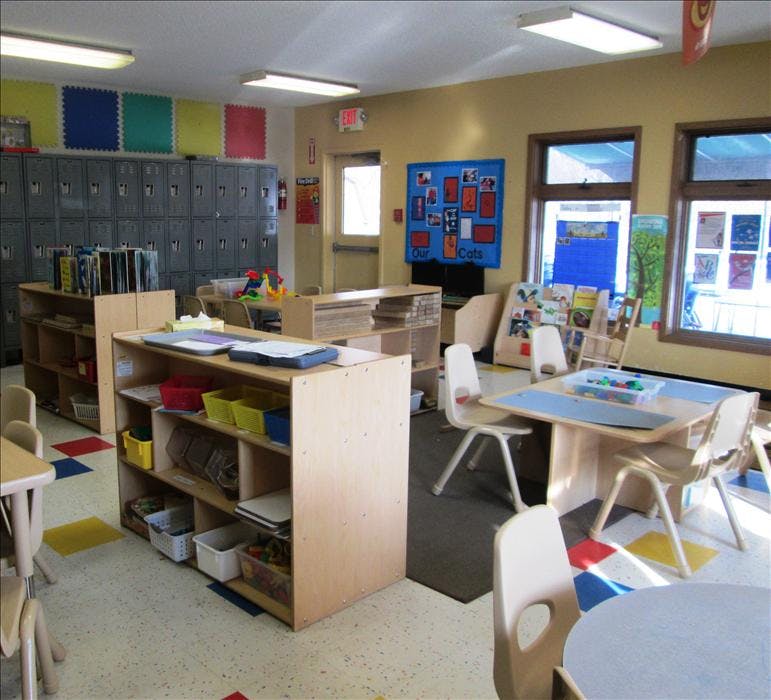 Classroom with small tables, chairs, and cubby shelves