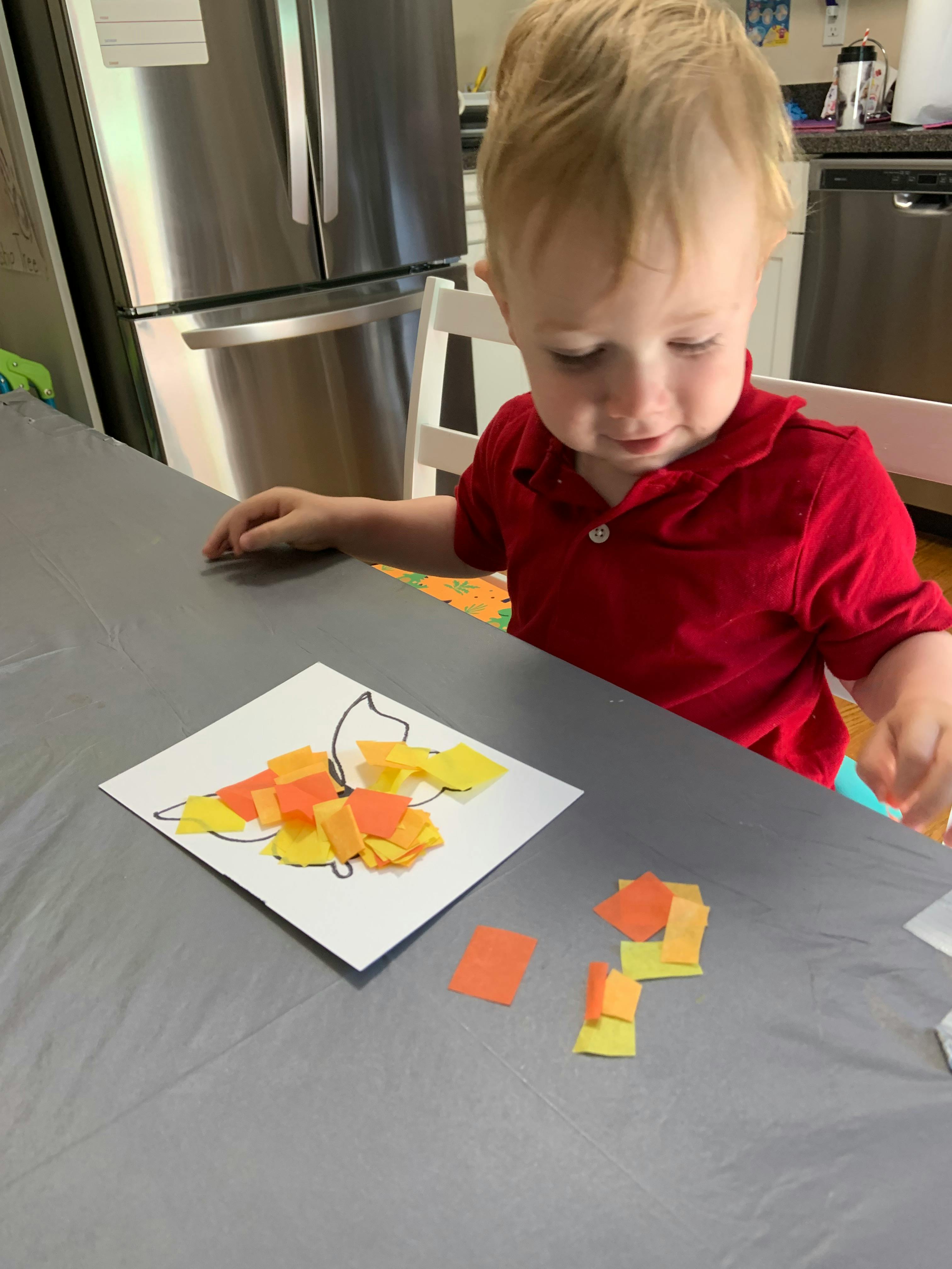 Child making a craft with paper pieces on a table