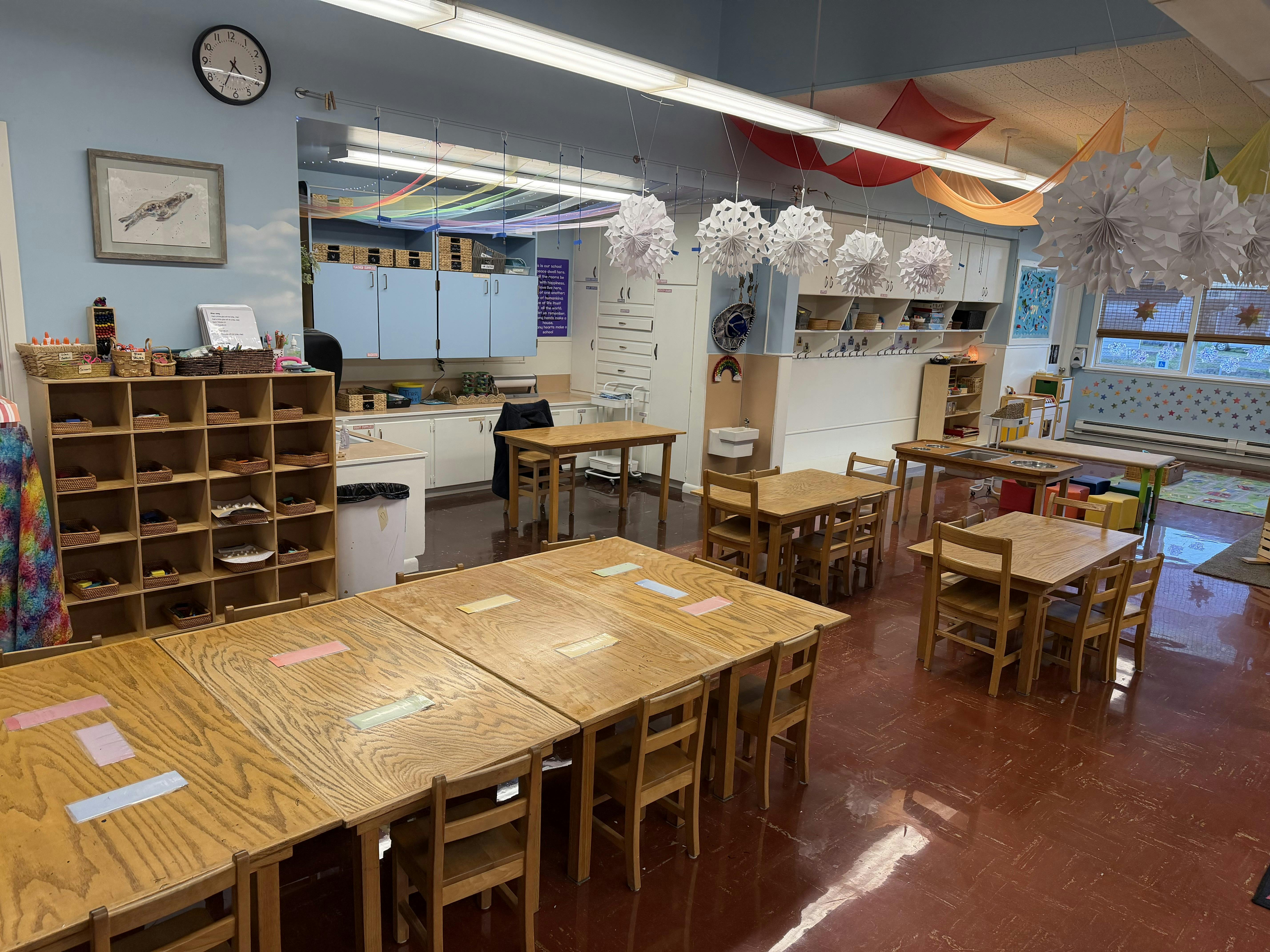 Empty classroom with small wooden tables and chairs