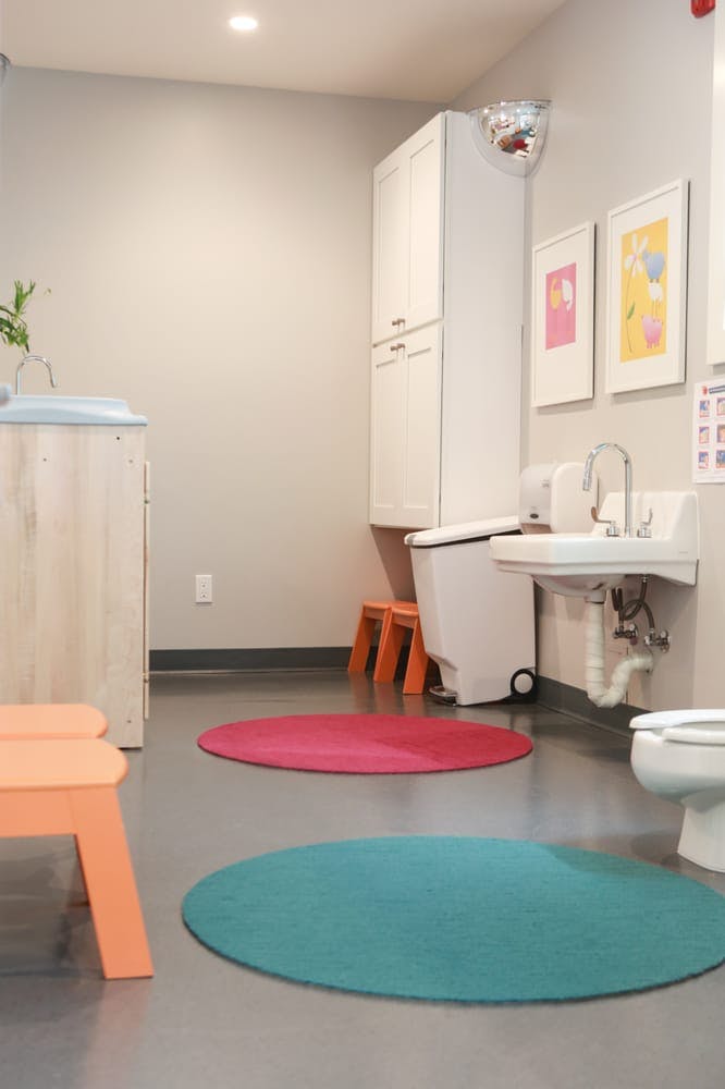 Bathroom with sink, toilet, changing table, and two round rugs