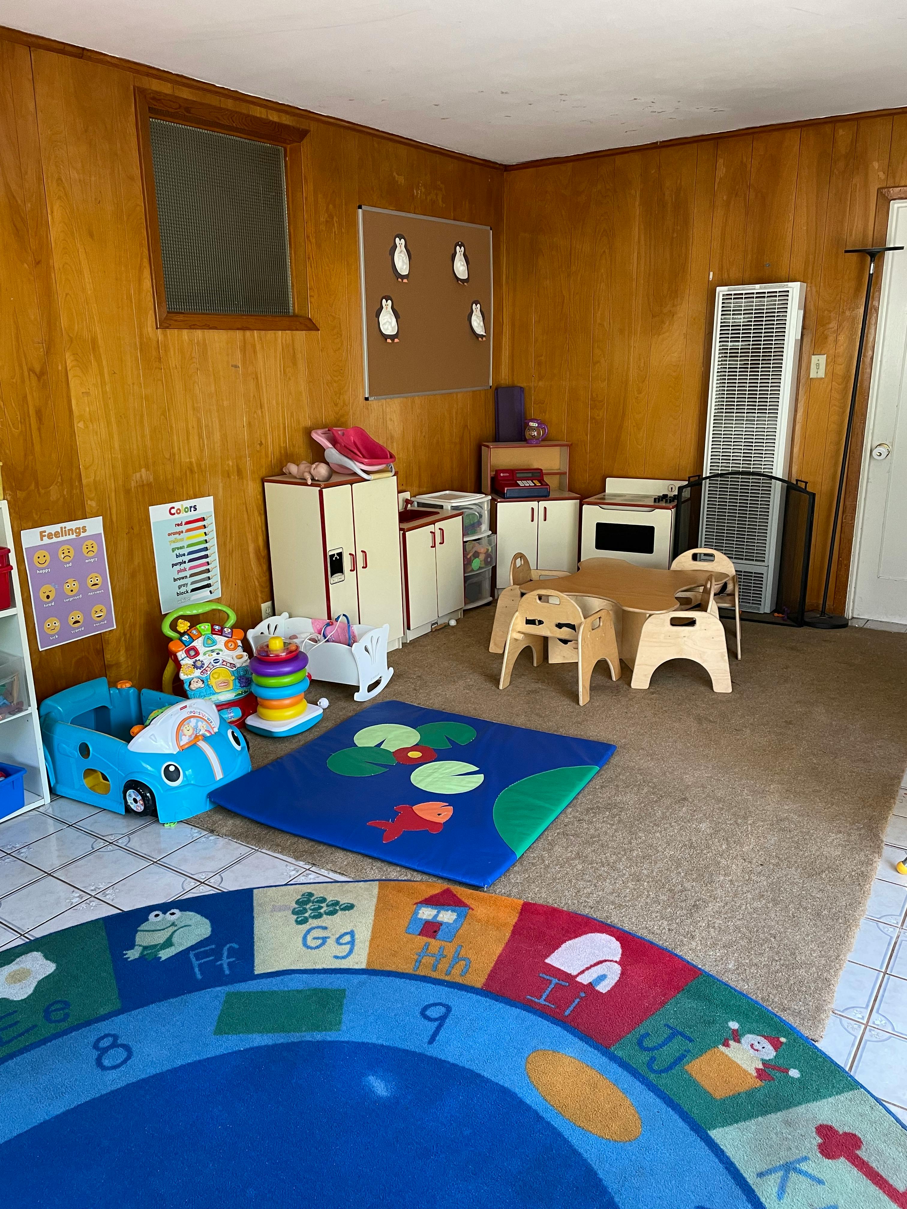 Playroom with small table and chairs, toy car, and colorful rugs