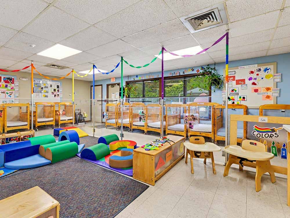 Cribs and soft play equipment in a classroom with ribbon streamers