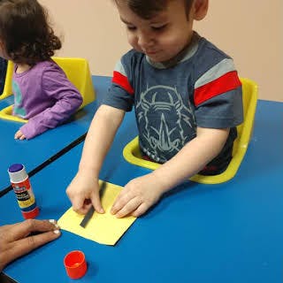 Child gluing paper at a table