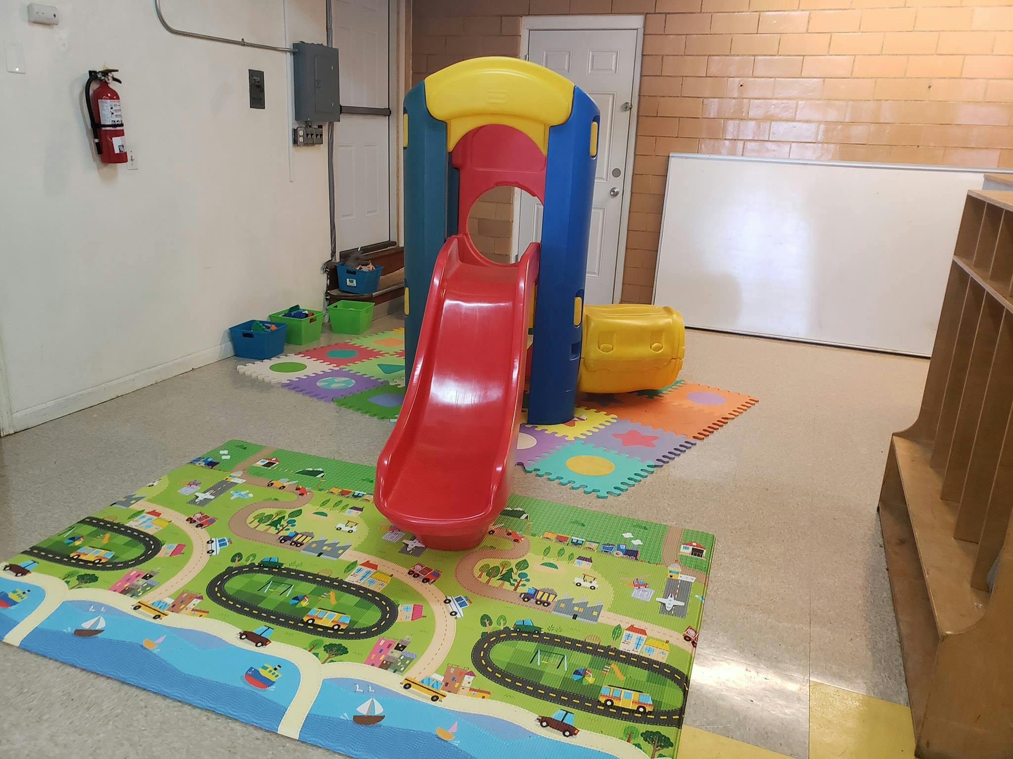 Indoor playground with a red slide and play mats