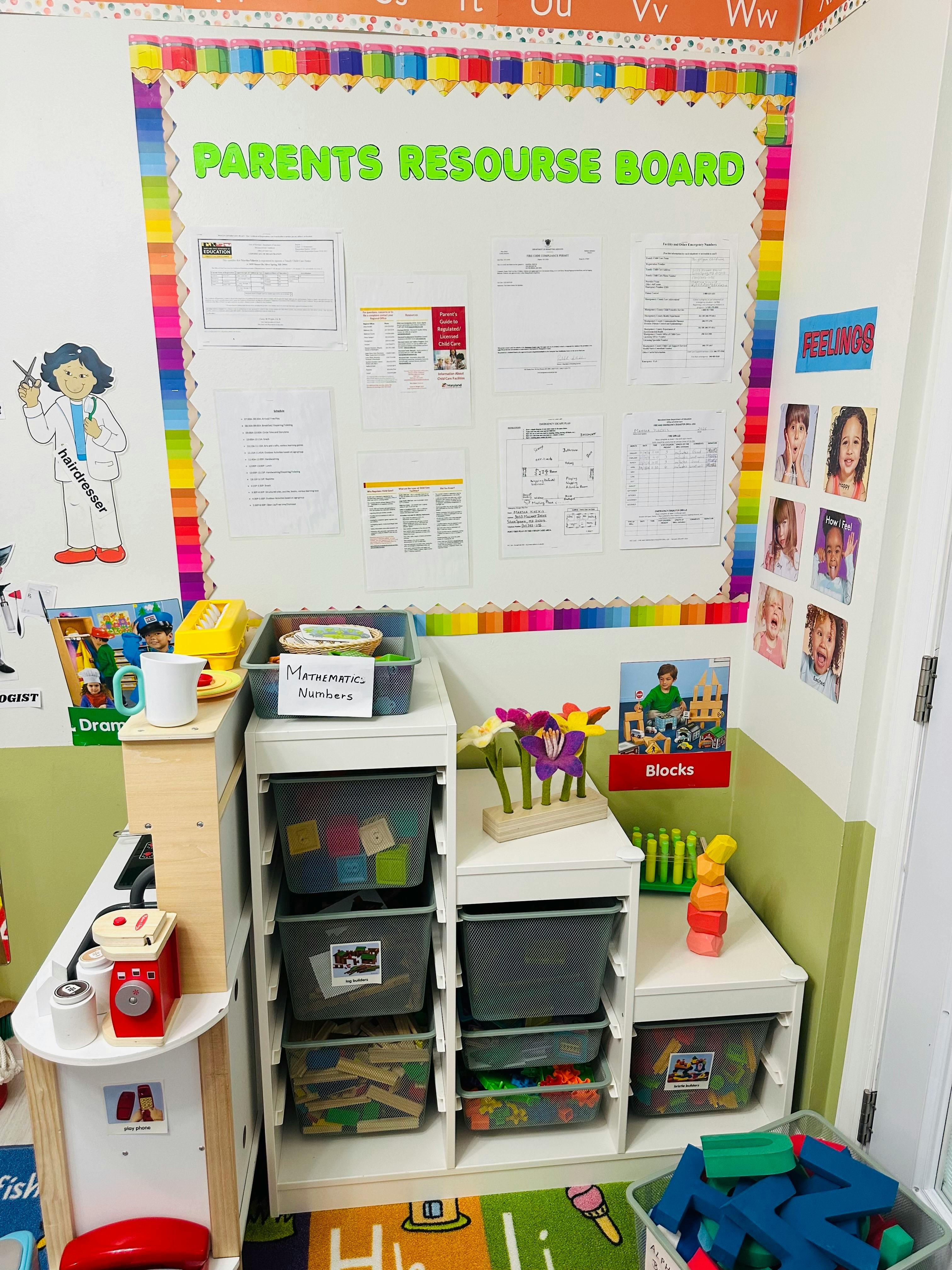 A classroom corner with a 'Parents Resource Board' and storage bins for toys