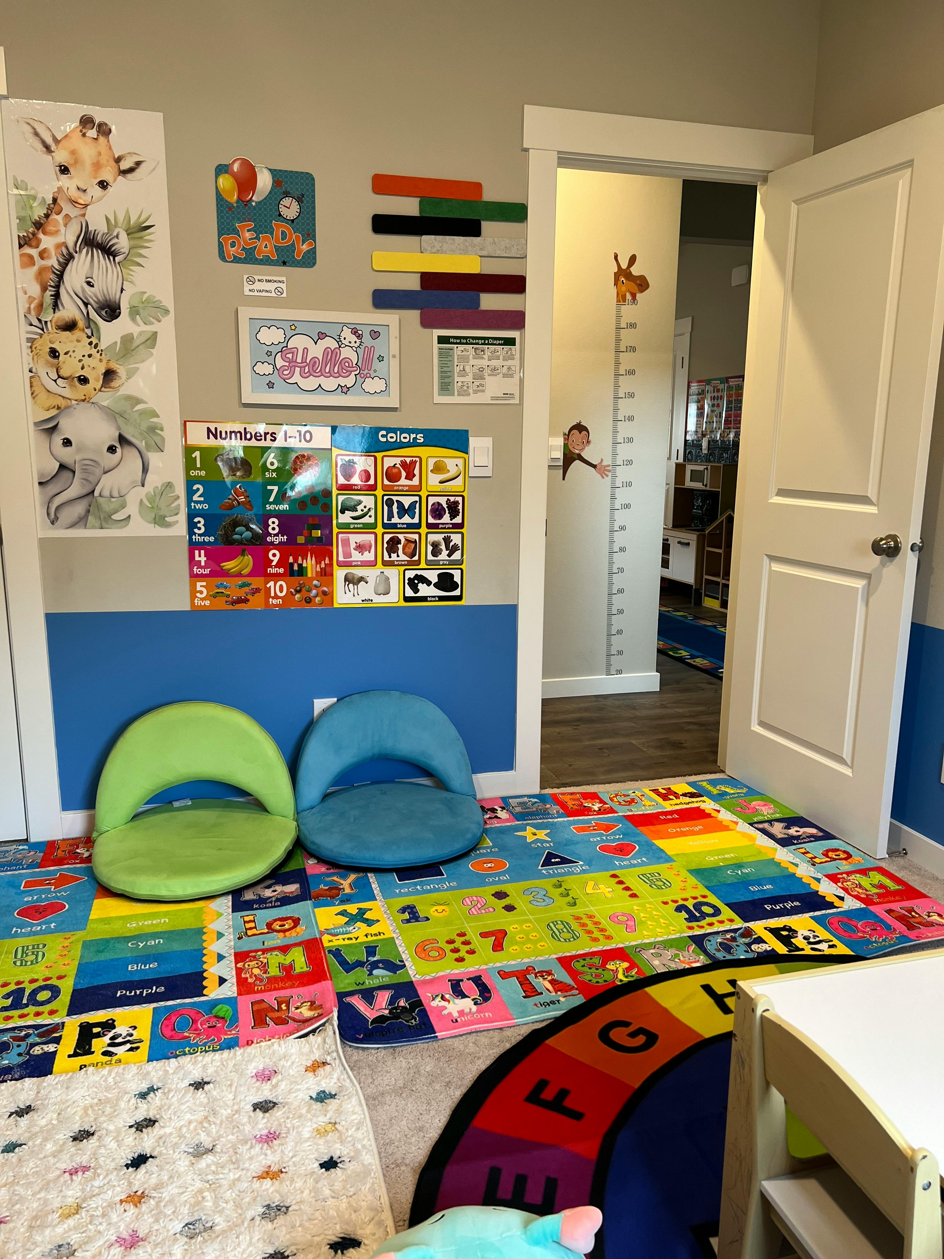 Children's play area with colorful alphabet rug, two floor chairs, and wall decorations