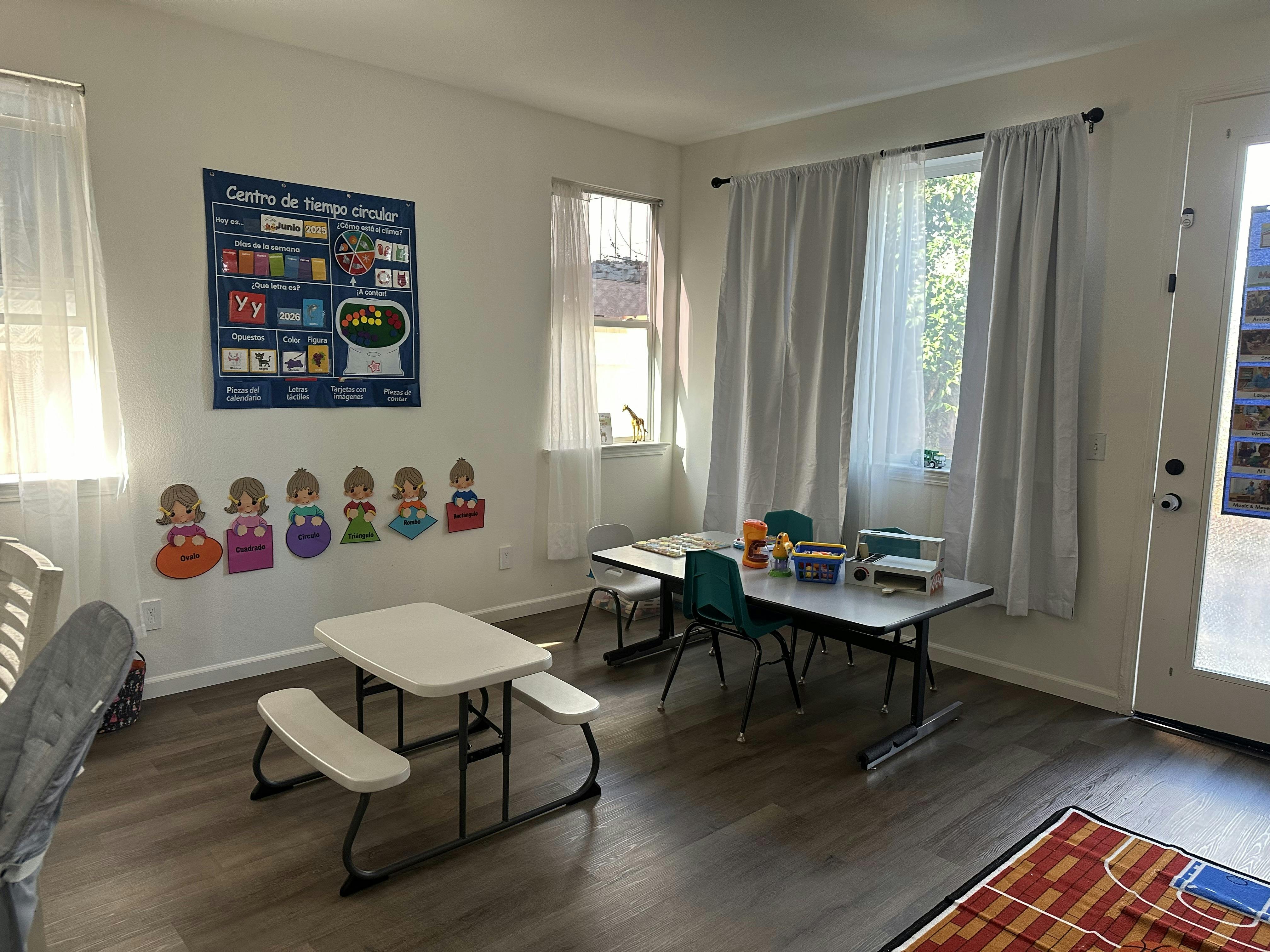 Classroom with small tables and chairs, a poster, and cutouts on the wall