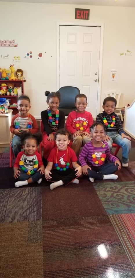 Seven children sitting and smiling in a classroom