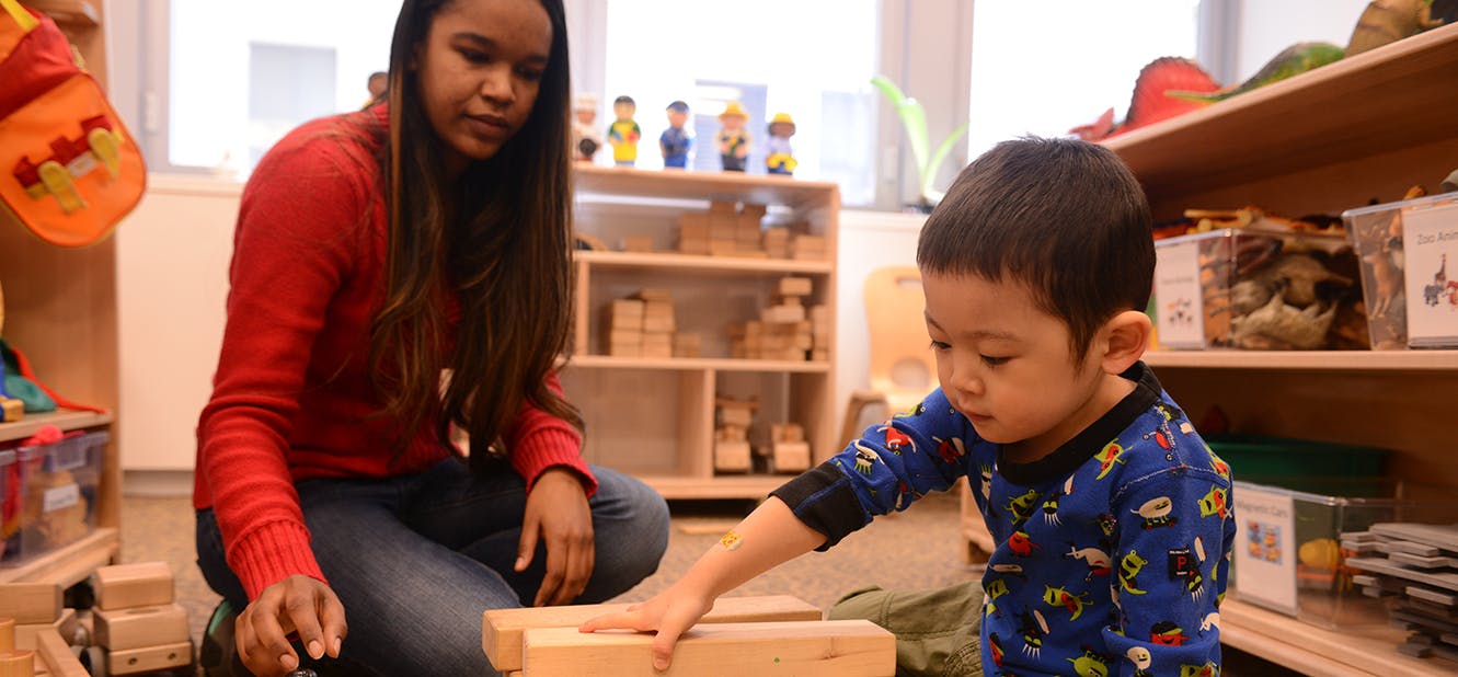Person and child playing with wooden blocks