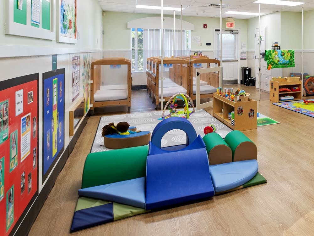 Cribs and padded play mats in an infant childcare room