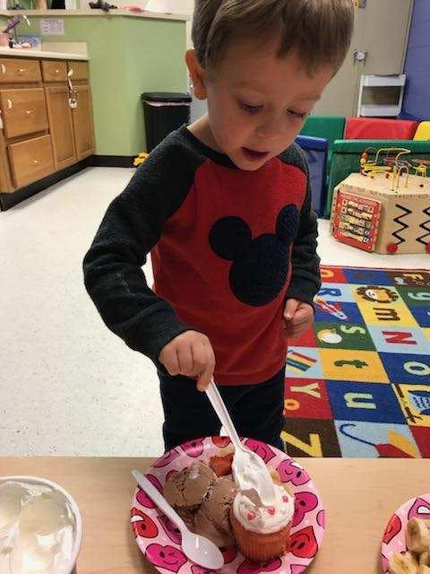 Child eating a cupcake and ice cream with a spoon