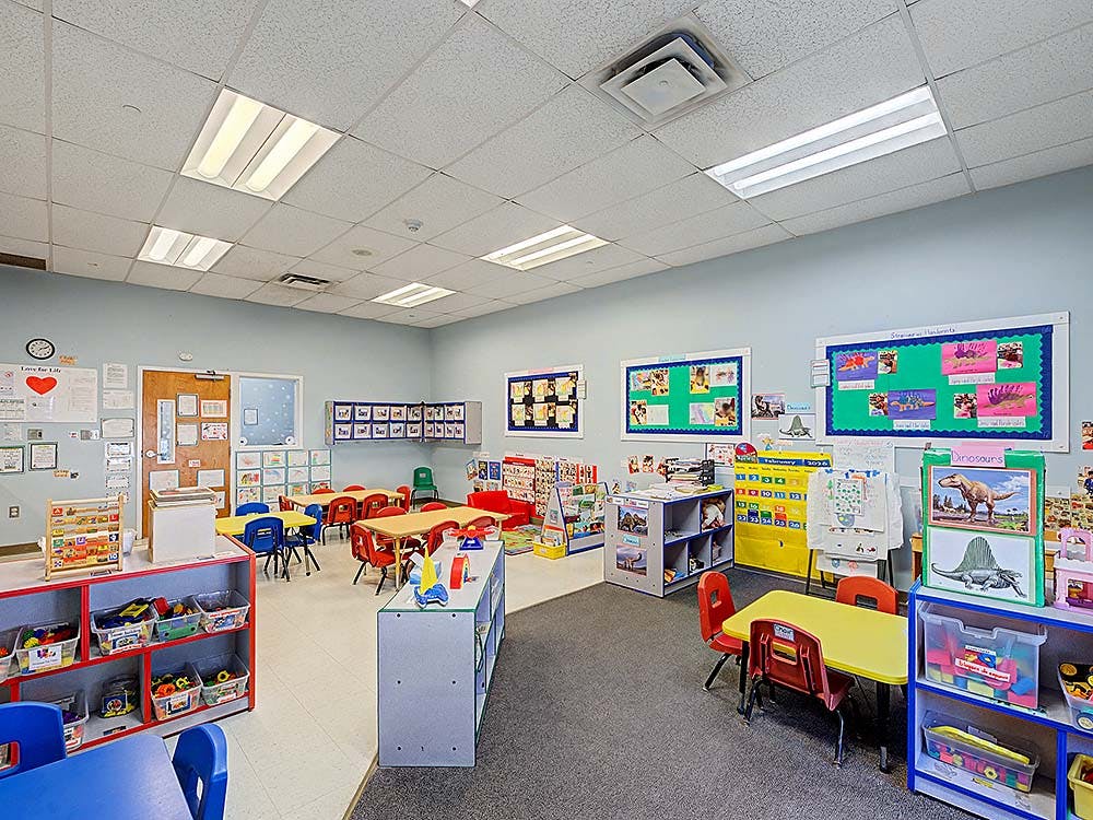 Classroom with small tables and chairs, bulletin boards on walls