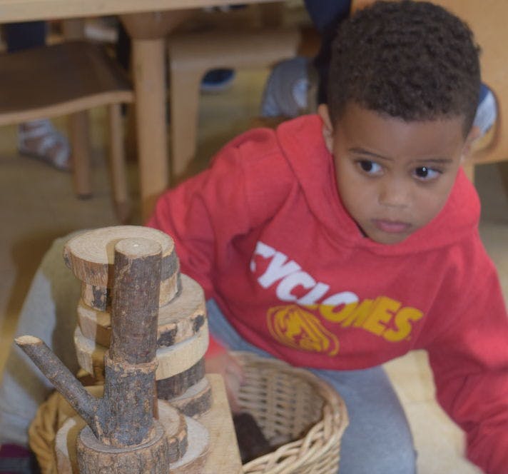 Child in red hoodie playing with wooden blocks