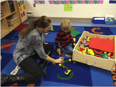 Adult and child playing with building blocks on a rug