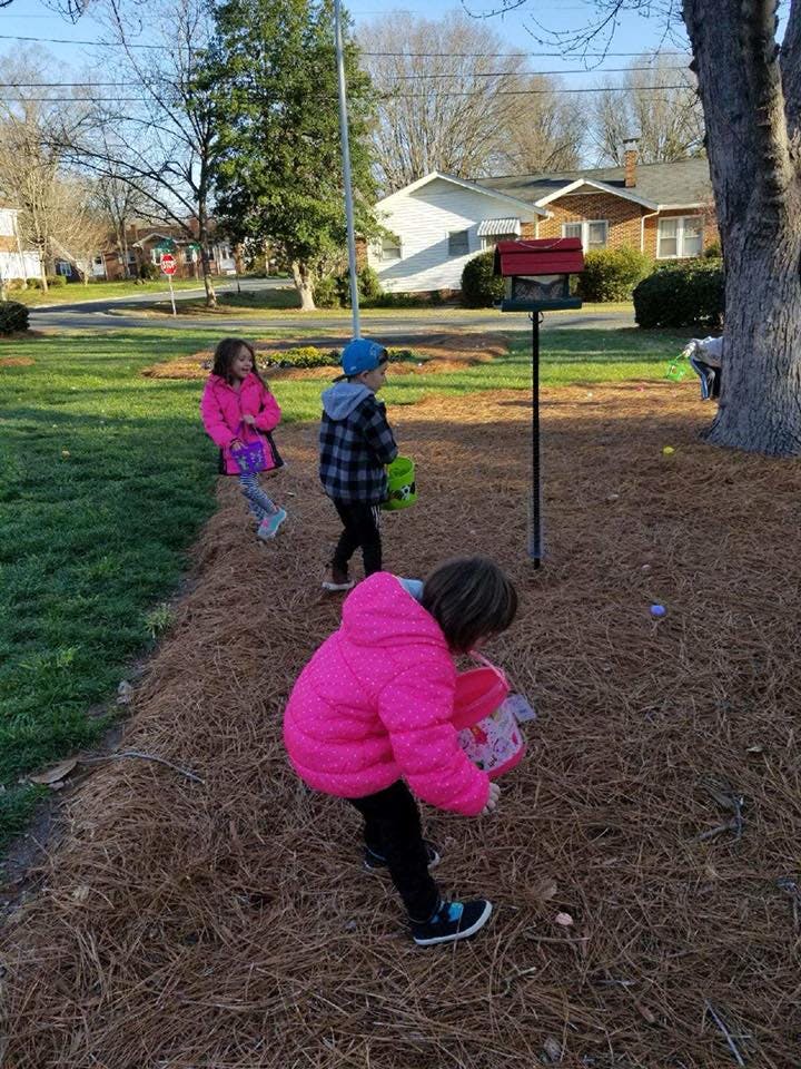 Three children searching for objects on the ground