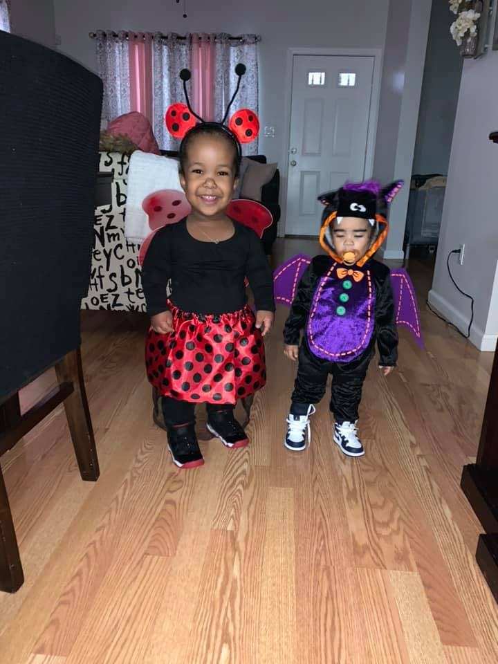 Two children in Halloween costumes, one as a ladybug and one as a bat