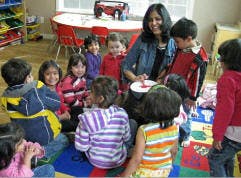 Adult and children gathered around a table in a classroom
