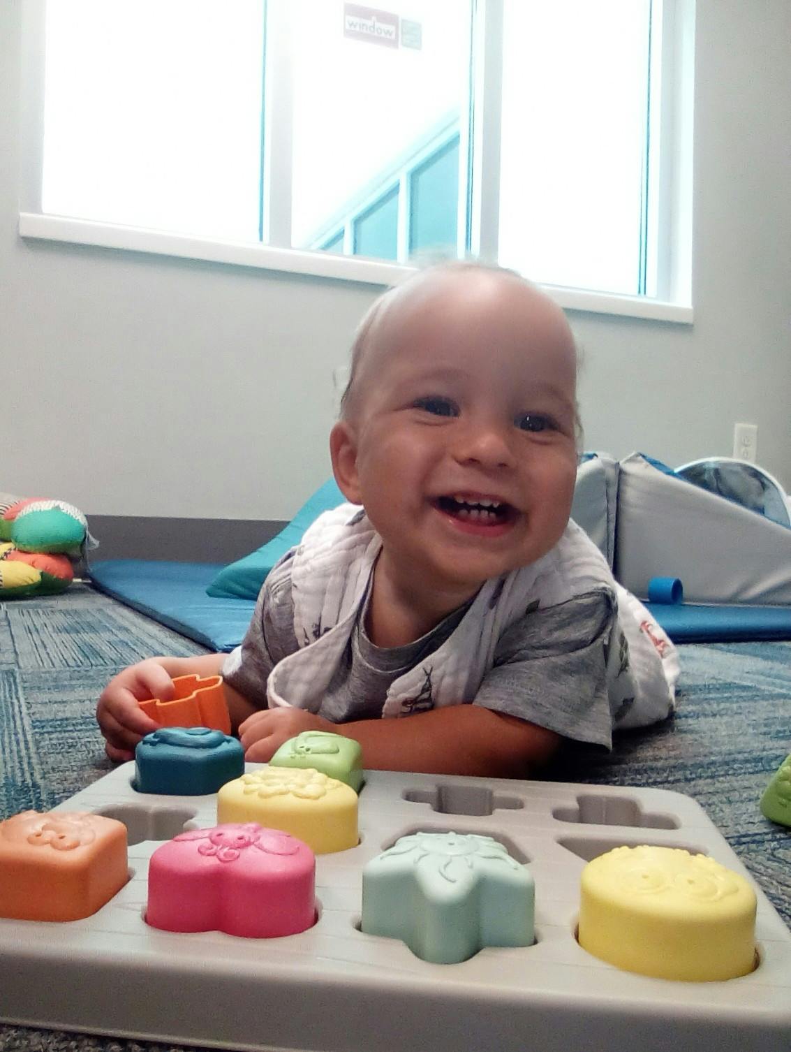 Smiling child on floor with shape sorting toy